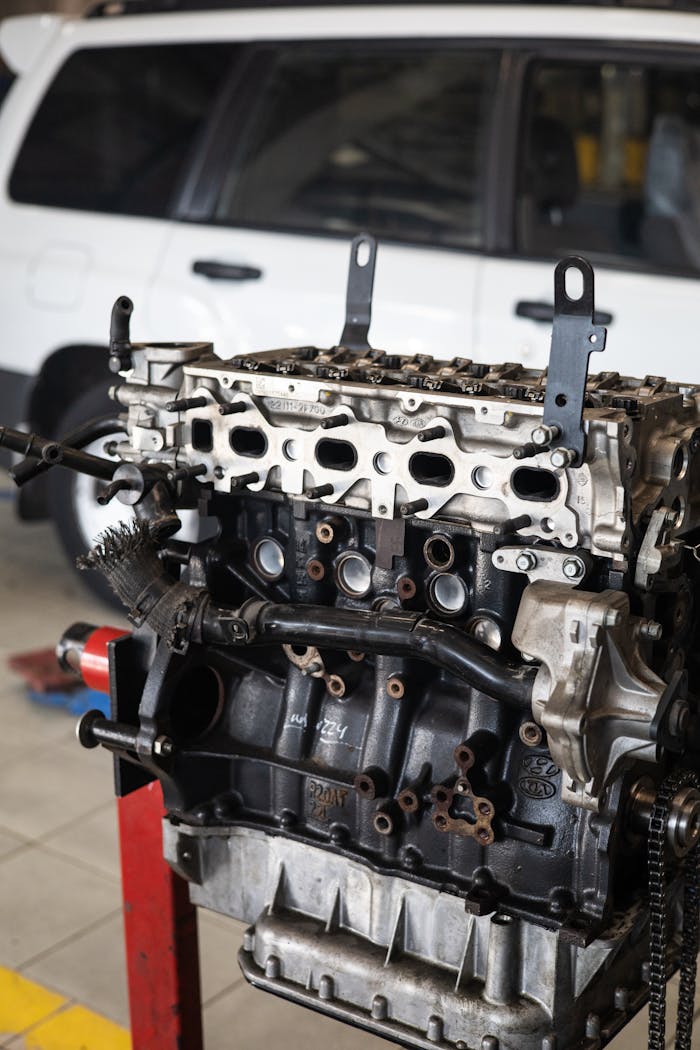 Detailed view of a car engine in an auto repair shop with a blurred vehicle in the background.